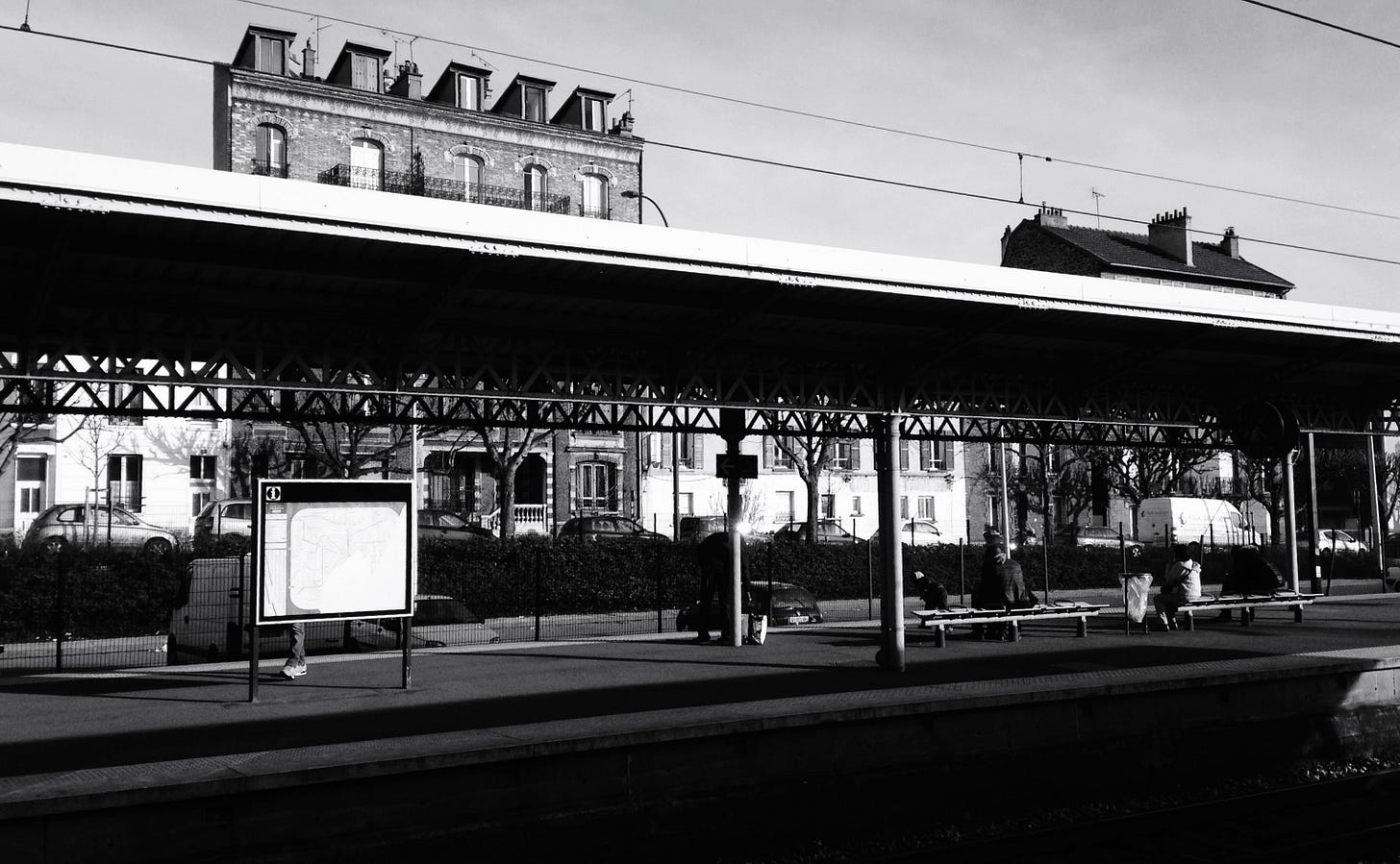 Black and greay image of an outdoor bus terminal with a brick building behind it