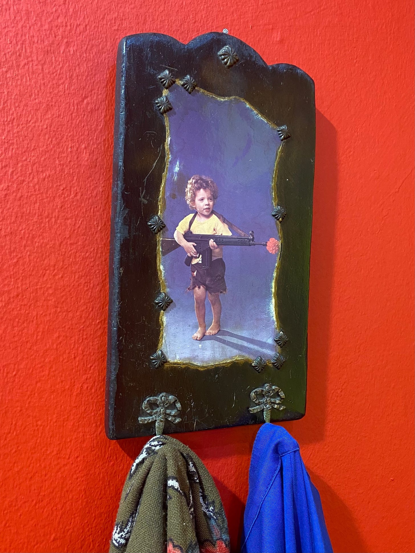 Young child holding a gun with a carnation flower in the barrel