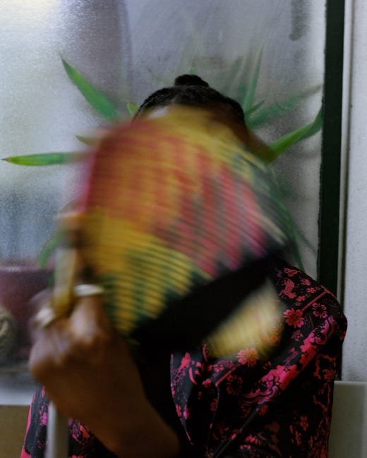 Une jeune photographiée derrière son éventail. Lui est flou et elle, cachée dans le flou.