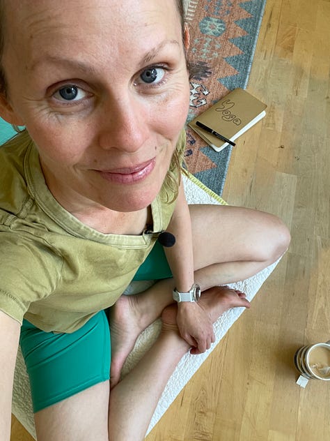 kelly in green t-shirt and darker green shorts, sitting cross-legged; painting kelly is working on; rudbeckia flowers-- yellow petals with brown centers