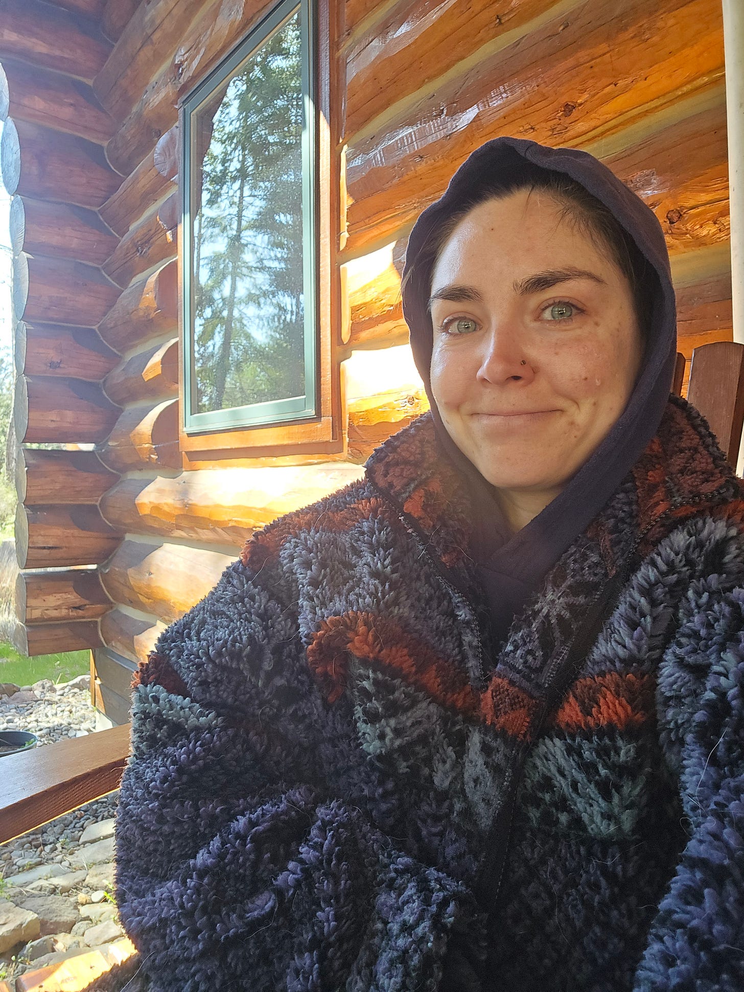 Cassidy sitting on a porch, bundled up in a sweater with the hood on, with a tear running down her cheek. Cassidy sitting on a porch, bundled up in a sweater with the hood on, with a tear running down her cheek.
