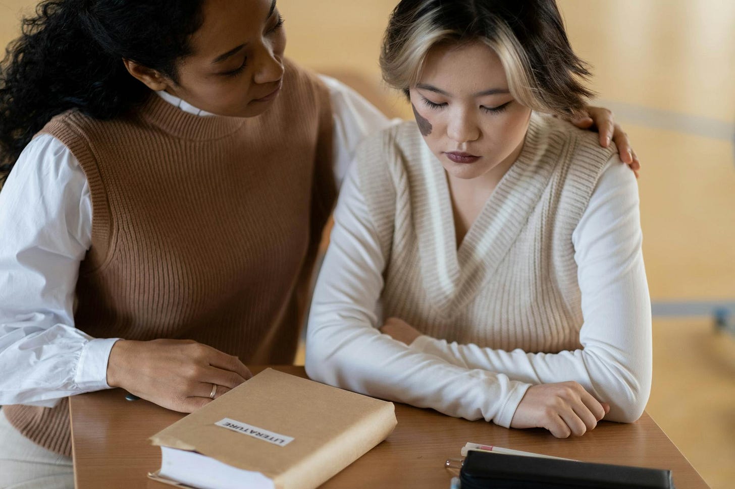 woman in white sweater sitting beside woman in brown sweater.