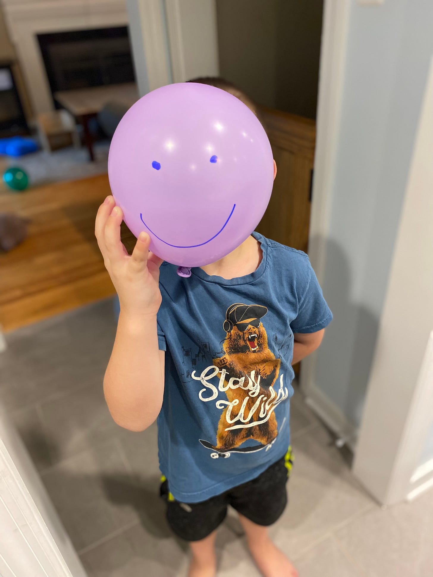 Child holding balloon with smiley face on it