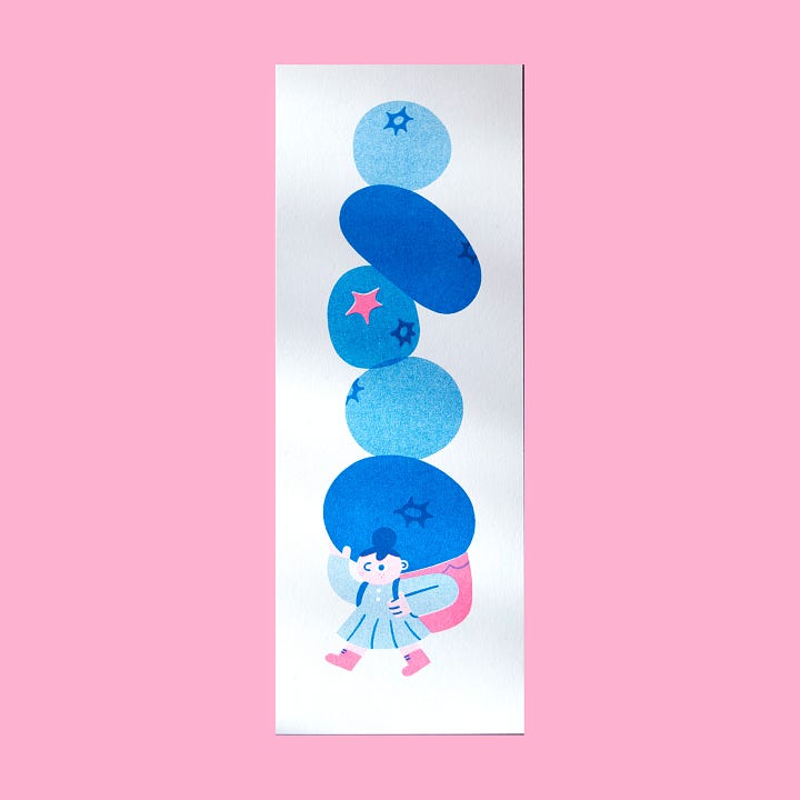 First photo: a risograph print of a lady carrying giant blueberries.  Second photo: a risograph notepad of a caterpillar.