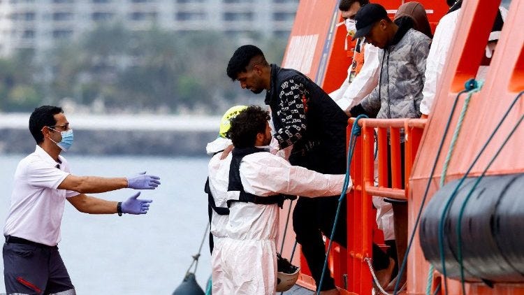 A rescuer helps a migrant disembark at Arguineguín A rescuer helps a migrant disembark at Arguineguín