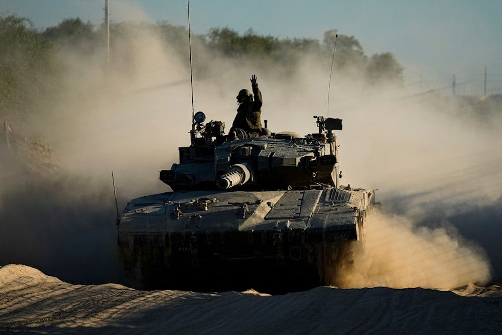 An Israeli soldier waves from a moving tank near the Gaza strip in southern occupied Palestine, Monday, Octpner 21, 2024 (AP) An Israeli soldier waves from a moving tank near the Gaza strip in southern occupied Palestine, Monday, Octpner 21, 2024 (AP)