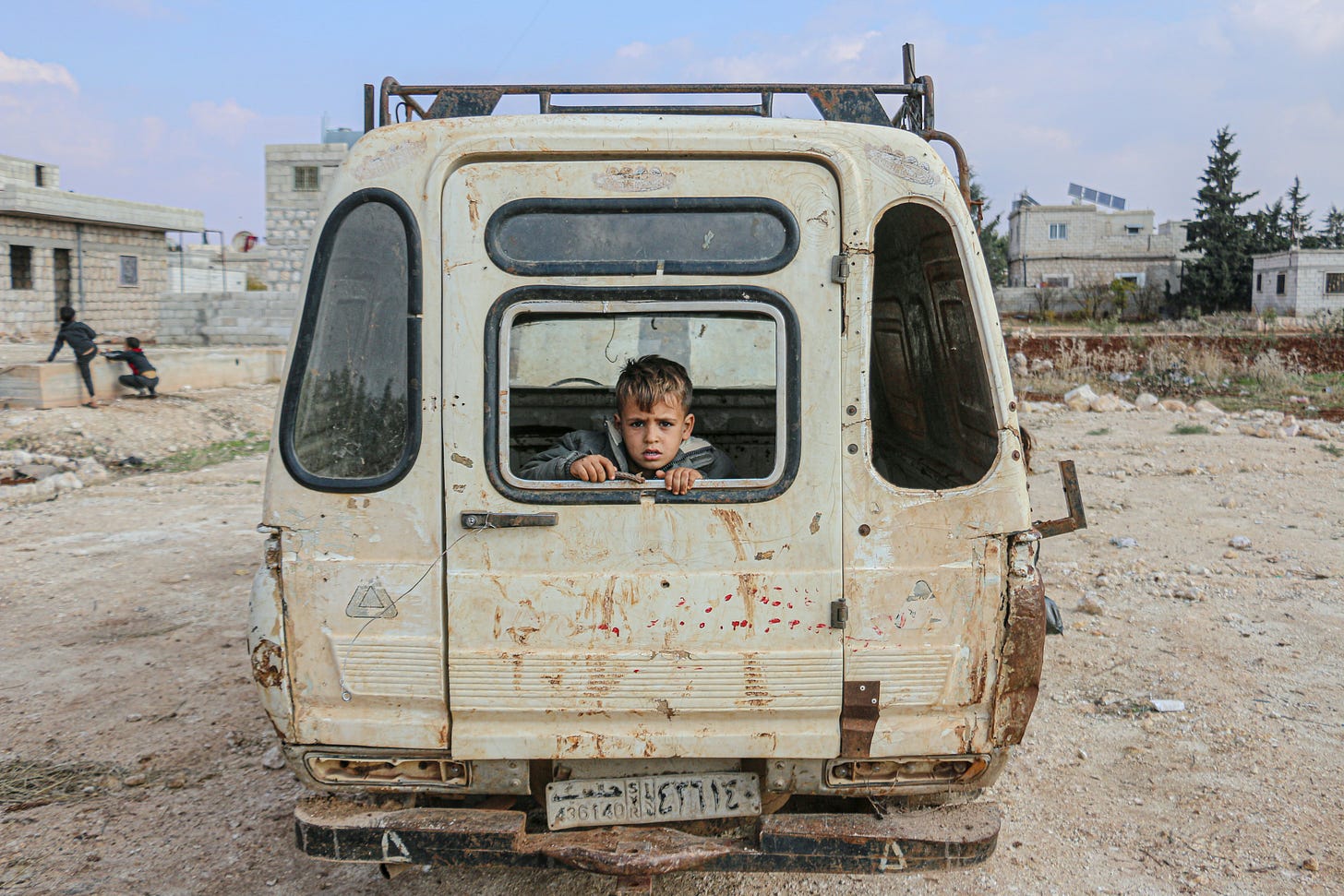 Poor boy sitting in a broken car. 
