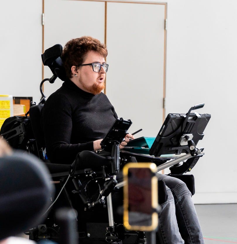 Jamie Hale, a white electric wheelchair user speaks to what one assumes is a group of people just out of shot