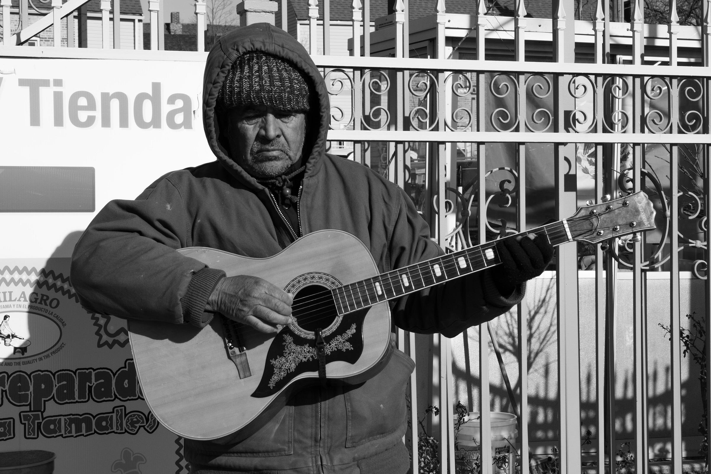 Black-and-white photo of man playing acoustic guitar.