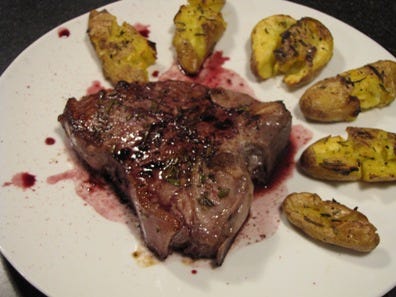 Veal chop with red wine reduction and roasted potatoes.