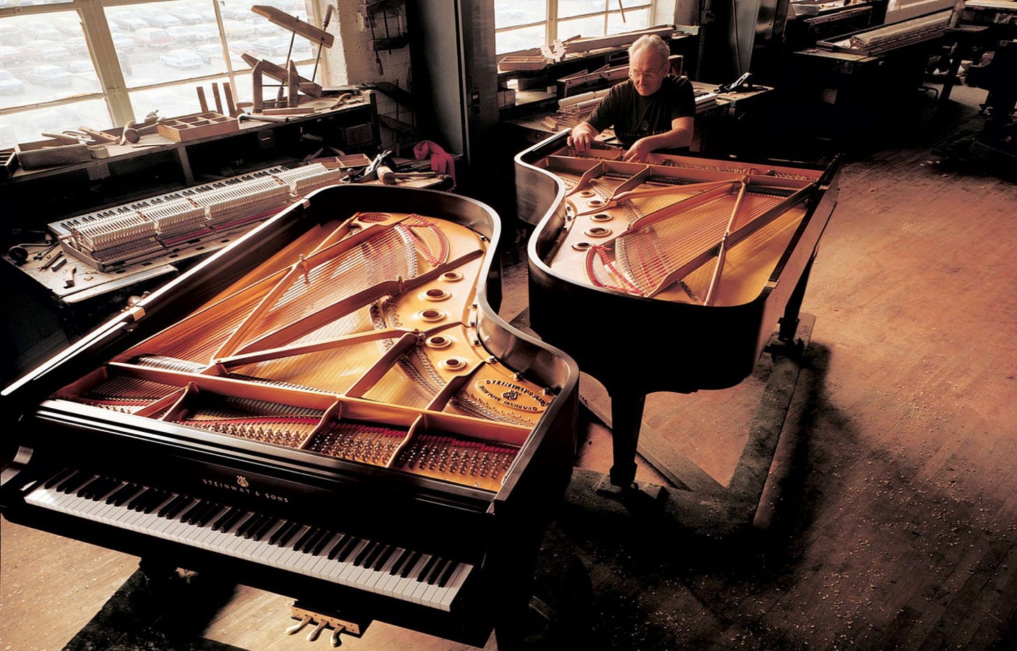 A Steinway piano technician puts the finishing touches on a pair of brand-new Steinway grand pianos.