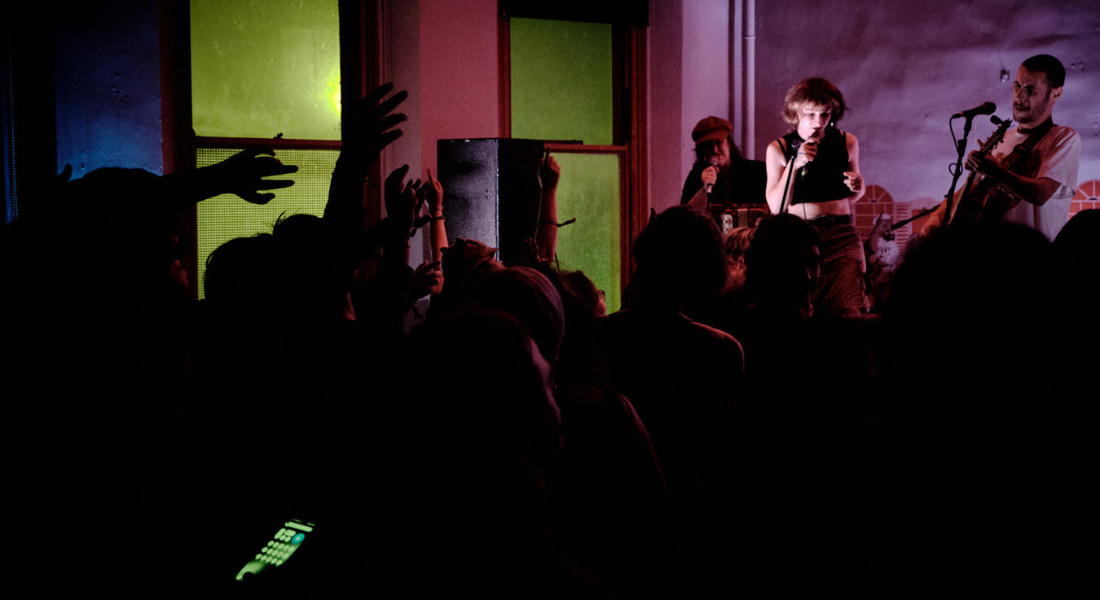 A crowd of people in front of a group of performers, with windows to the left A crowd of people in front of a group of performers, with windows to the left