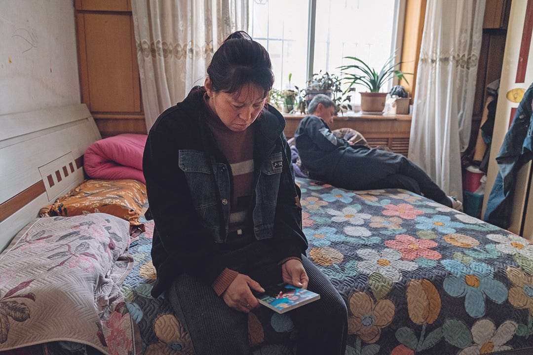 Qiqi’s mother sits on bed and gazes at Qiqi’s photo, as her husband sits on the other side of the bed on March 28 in Dalian, Liaoning province. Photo: Zheng Haipeng/Caixin