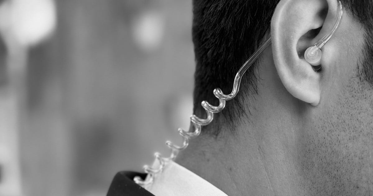 Profile view of a man with an FBI-style earpiece in his ear.