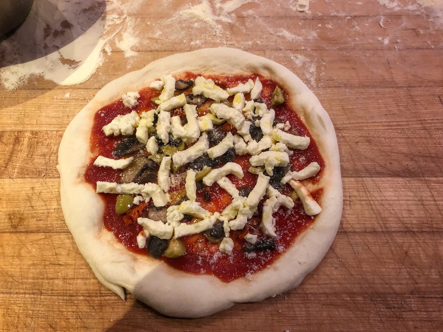 The disk of pizza dough, now covered in tomato sauce, cheese, and other toppings