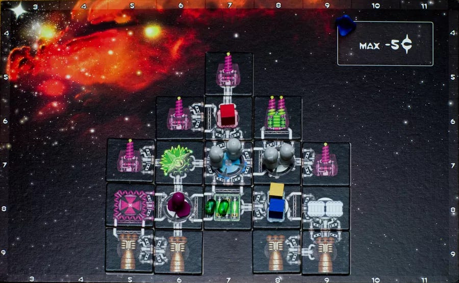 A small ship of Galaxy Trucker tiles, with guns facing forward, engines facing back, and cubes and components set atop the various components of the ship.