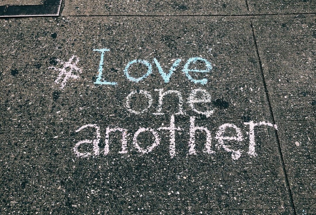 love one another chalk written on concrete floor