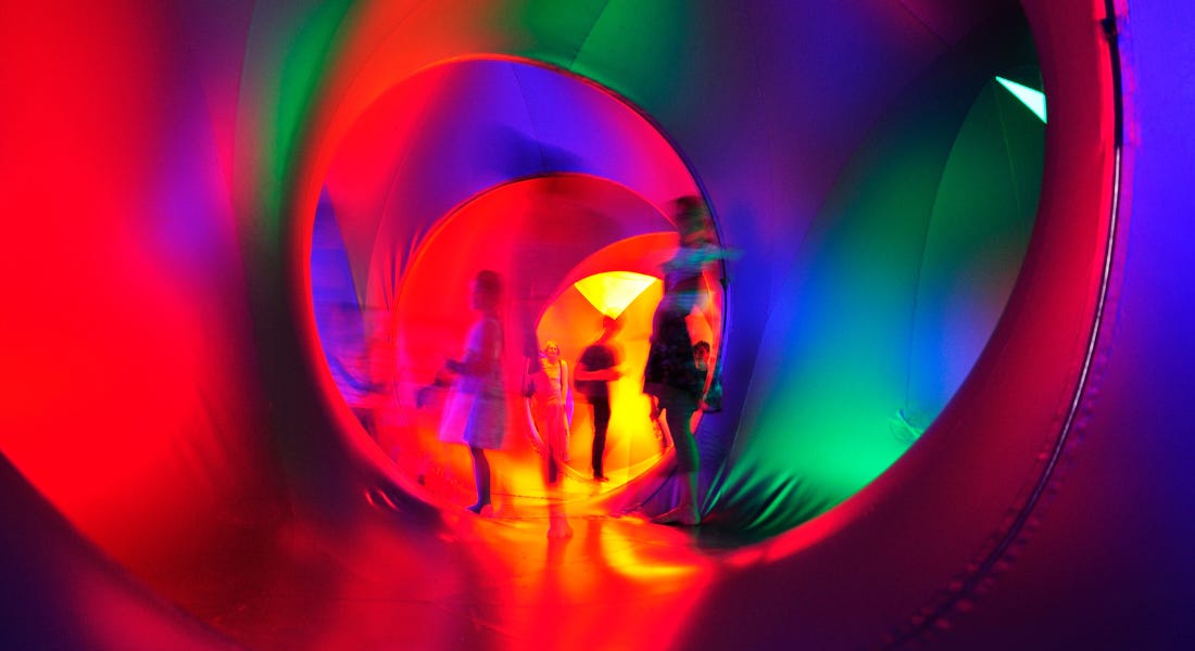 A colourful inflatable interior with red, green, and purple colours and people walking around inside