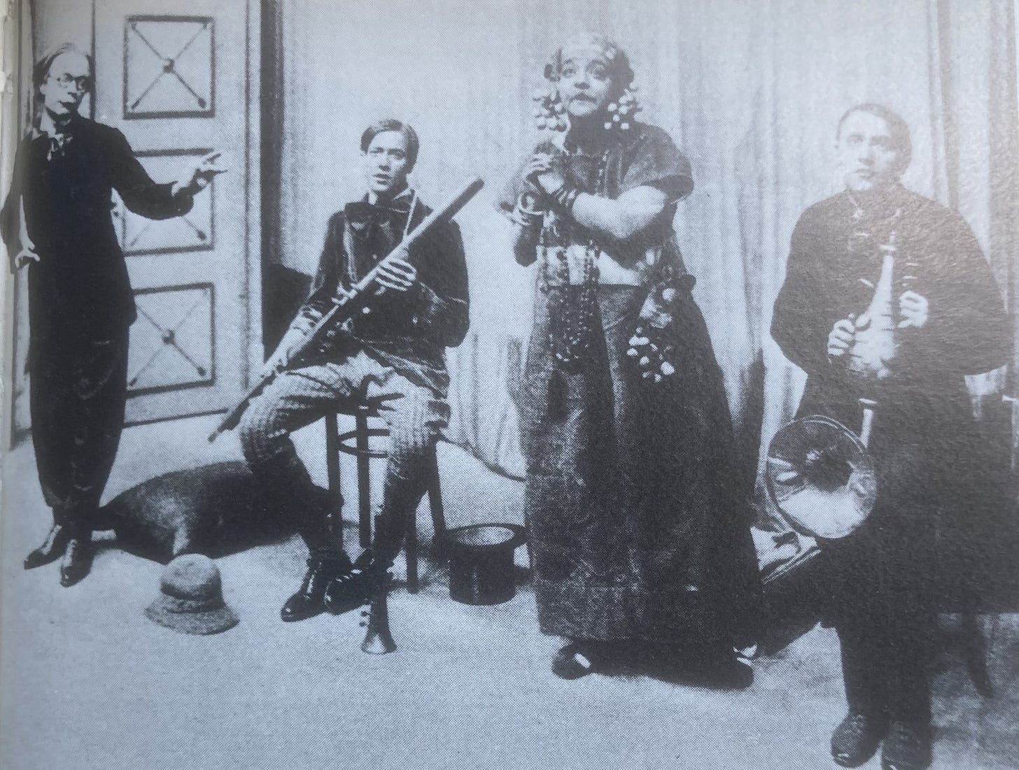 Swiss Family Whittlebot sketch: three bizarre-looking men and an arguable even more odd woman in a row, in odd poses, carrying weird musical instruments. The woman wears a robe and eccentric jewellery and has her hands clasped melodramatically