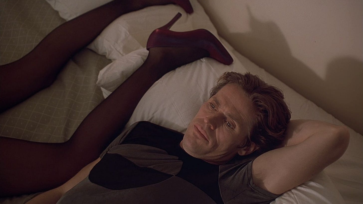 New Rose Hotel | Still features Willem Dafoe as X lying in bed next to Sandii, whose legs are shown.