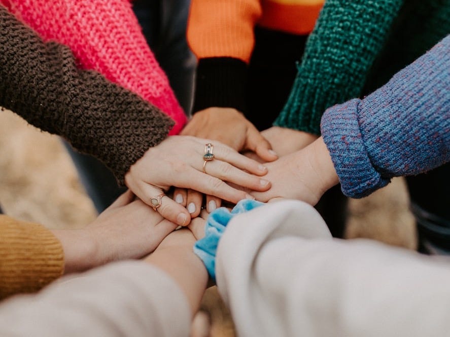 person in red sweater holding babys hand