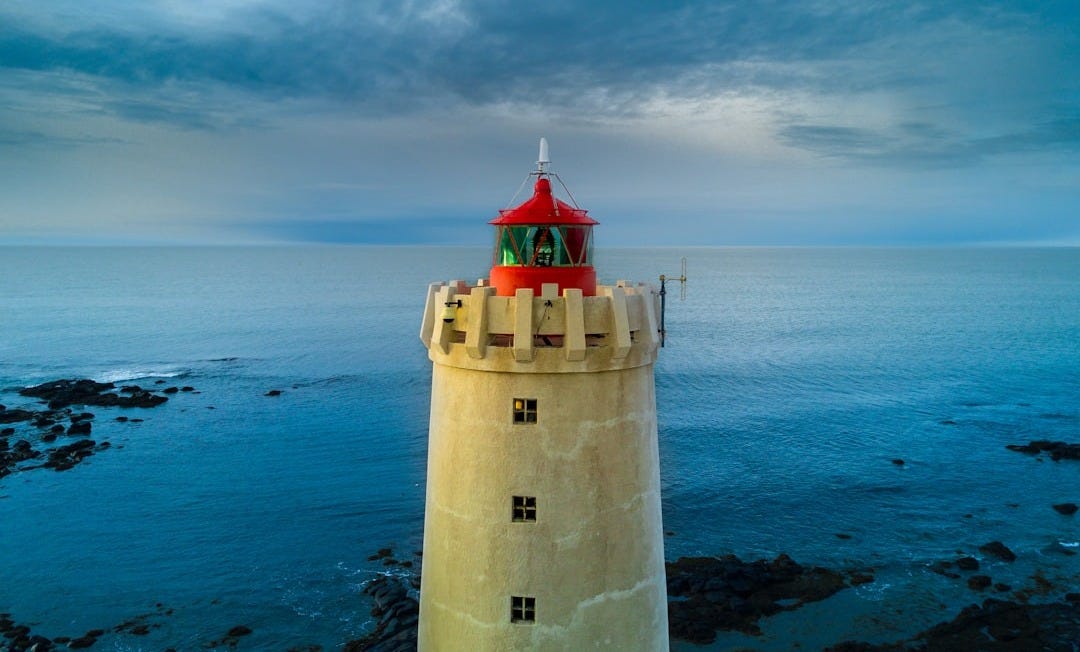 yellow and red lighthouse near body of water at daytime