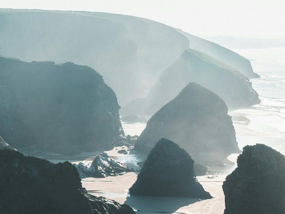 grayscale photography of rocky mountains and beach grayscale photography of rocky mountains and beach