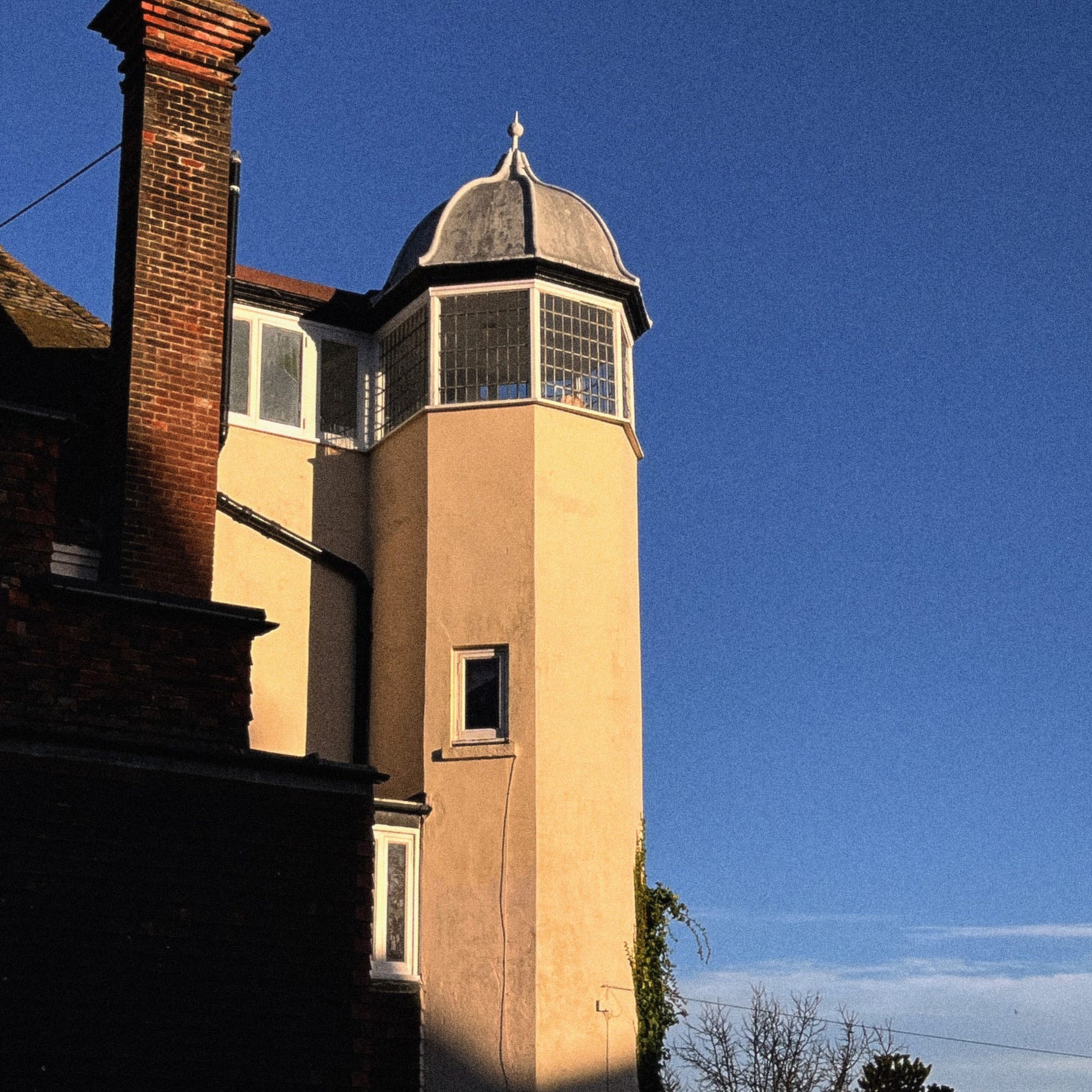 A smal tower on the side of a house