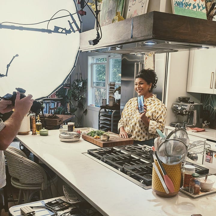 Aarti Sequeira's home kitchen, with Compassion international - dishes at the stove, film crew, food