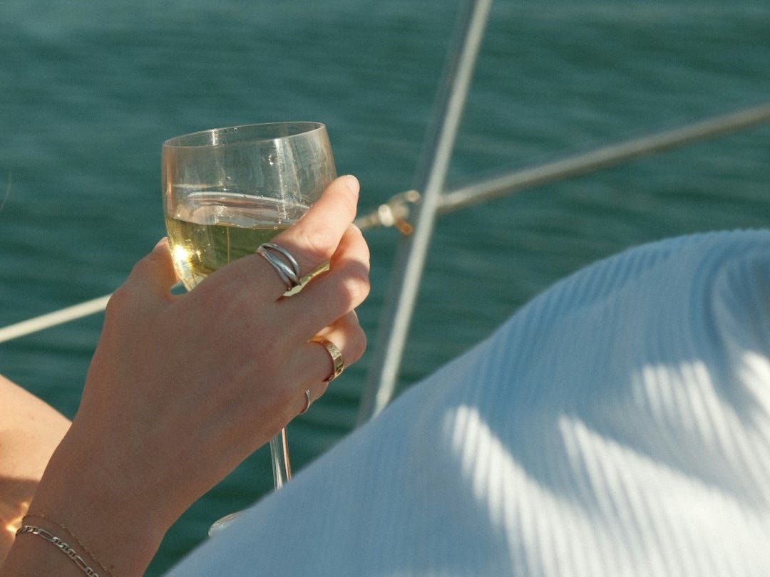 A woman sitting on a boat holding a glass of wine A woman sitting on a boat holding a glass of wine