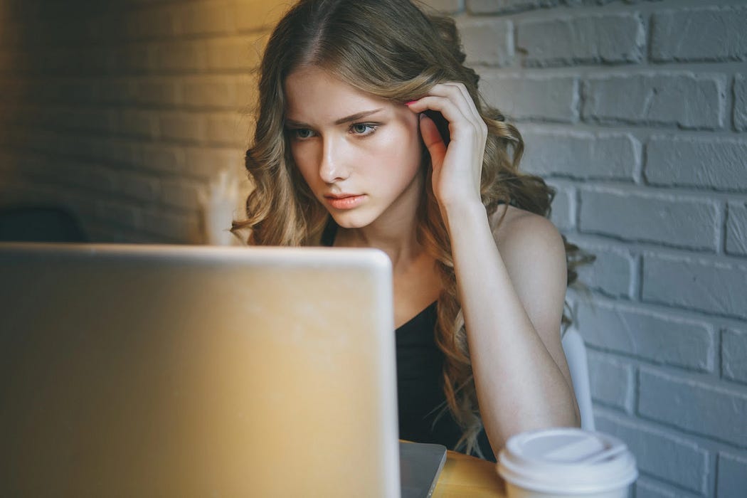A beautiful girl with curly blond hair stares at her laptop. A beautiful girl with curly blond hair stares at her laptop.
