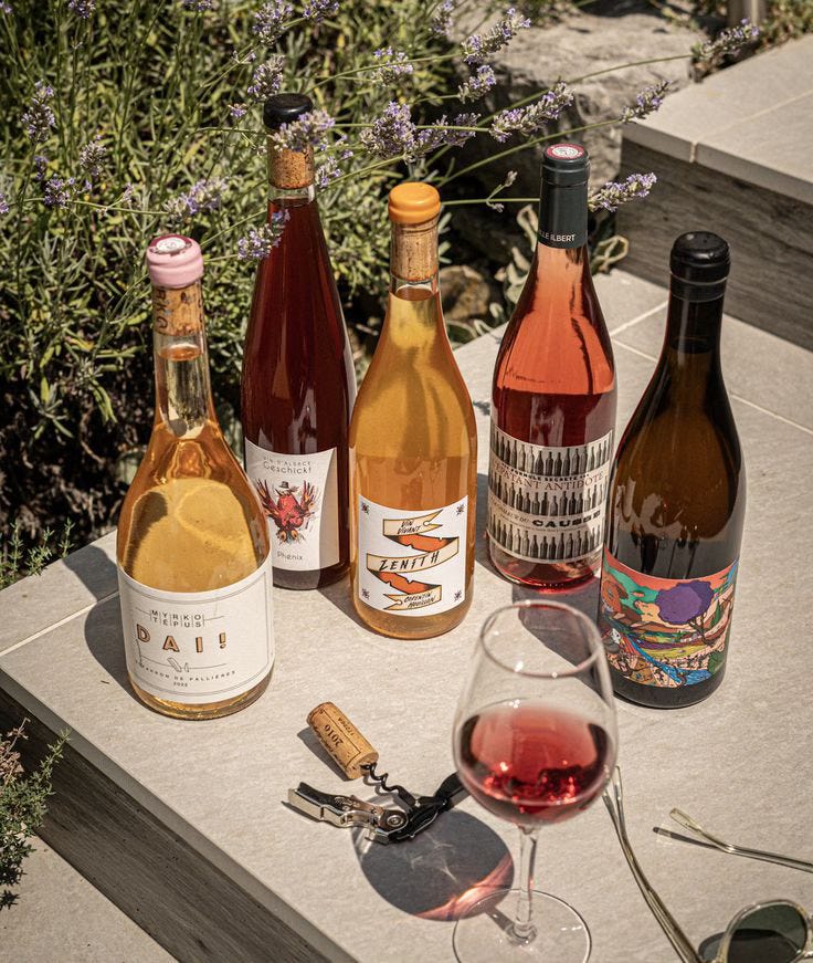 Bottles and a poured glass of natural wine on a wooden bar in Bali, the cloudy low-intervention style typical of the natural wine bars now popping up across Canggu and Seminyak. Bottles and a poured glass of natural wine on a wooden bar in Bali, the cloudy low-intervention style typical of the natural wine bars now popping up across Canggu and Seminyak.