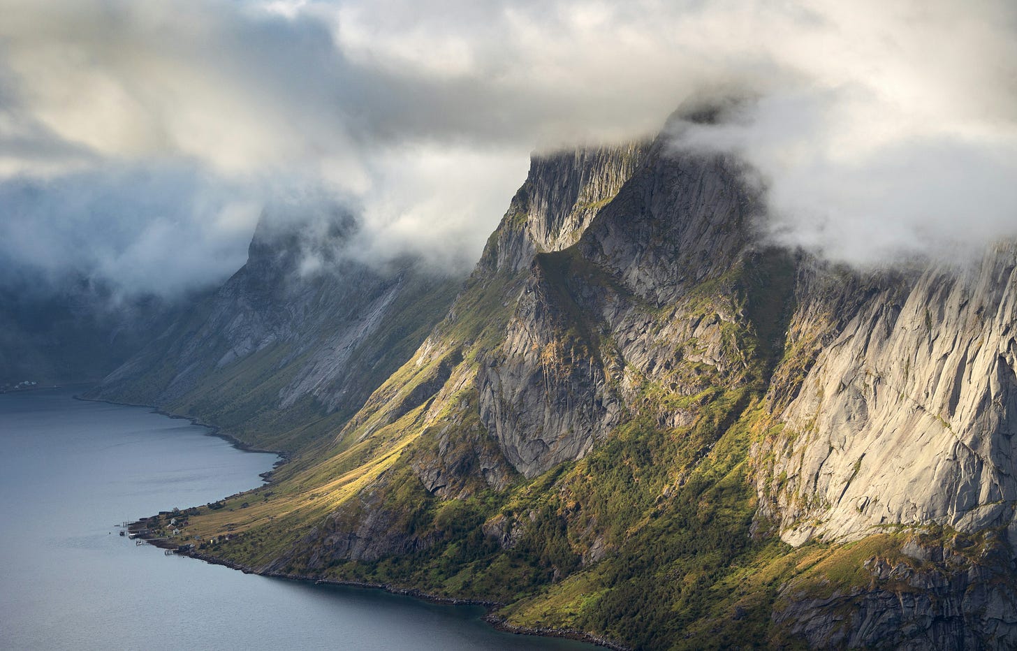 Image of mountains emerging from the sea into clouds in Reine, Norway.
