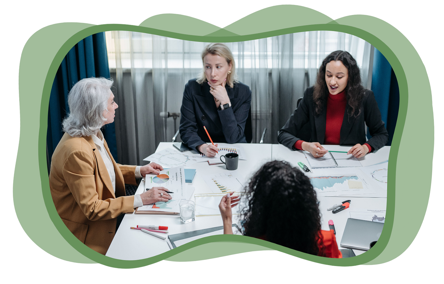 A group of four women sit around a conference table having a meeting.