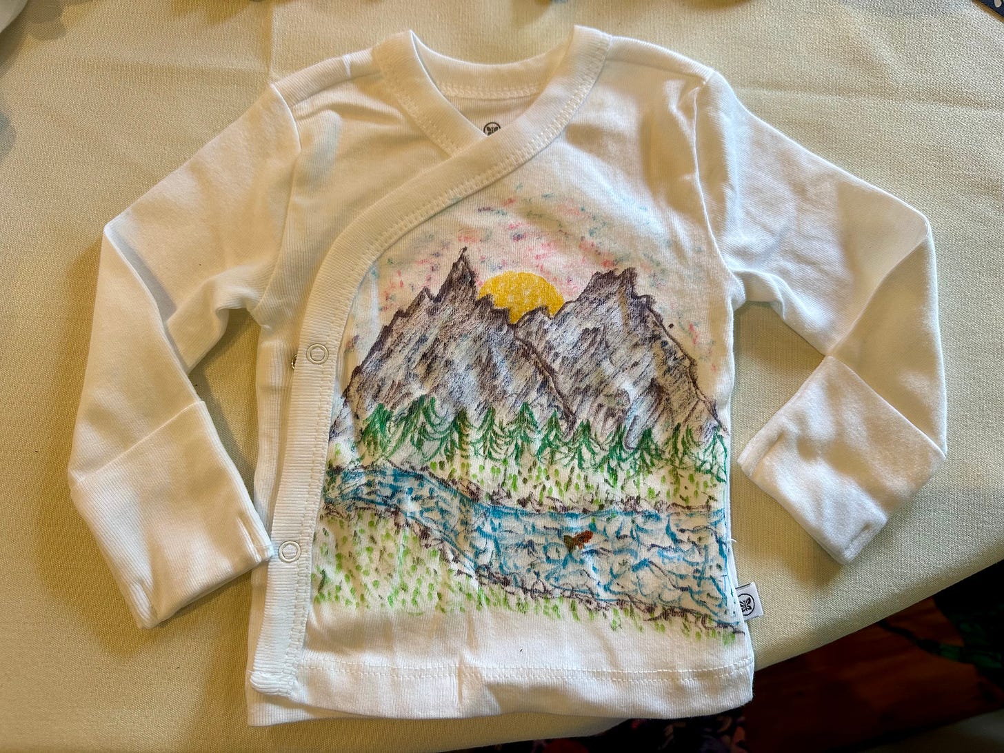White baby shirt with drawing of a mountain scene