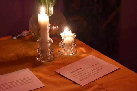 pictures of author signing book at book launch event, and aesthic placement of candles, dim light, and books displayed in accordion style