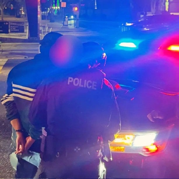 Police officers arresting a suspect at night with flashing lights in the background, highlighting a law enforcement situation. Police officers arresting a suspect at night with flashing lights in the background, highlighting a law enforcement situation.