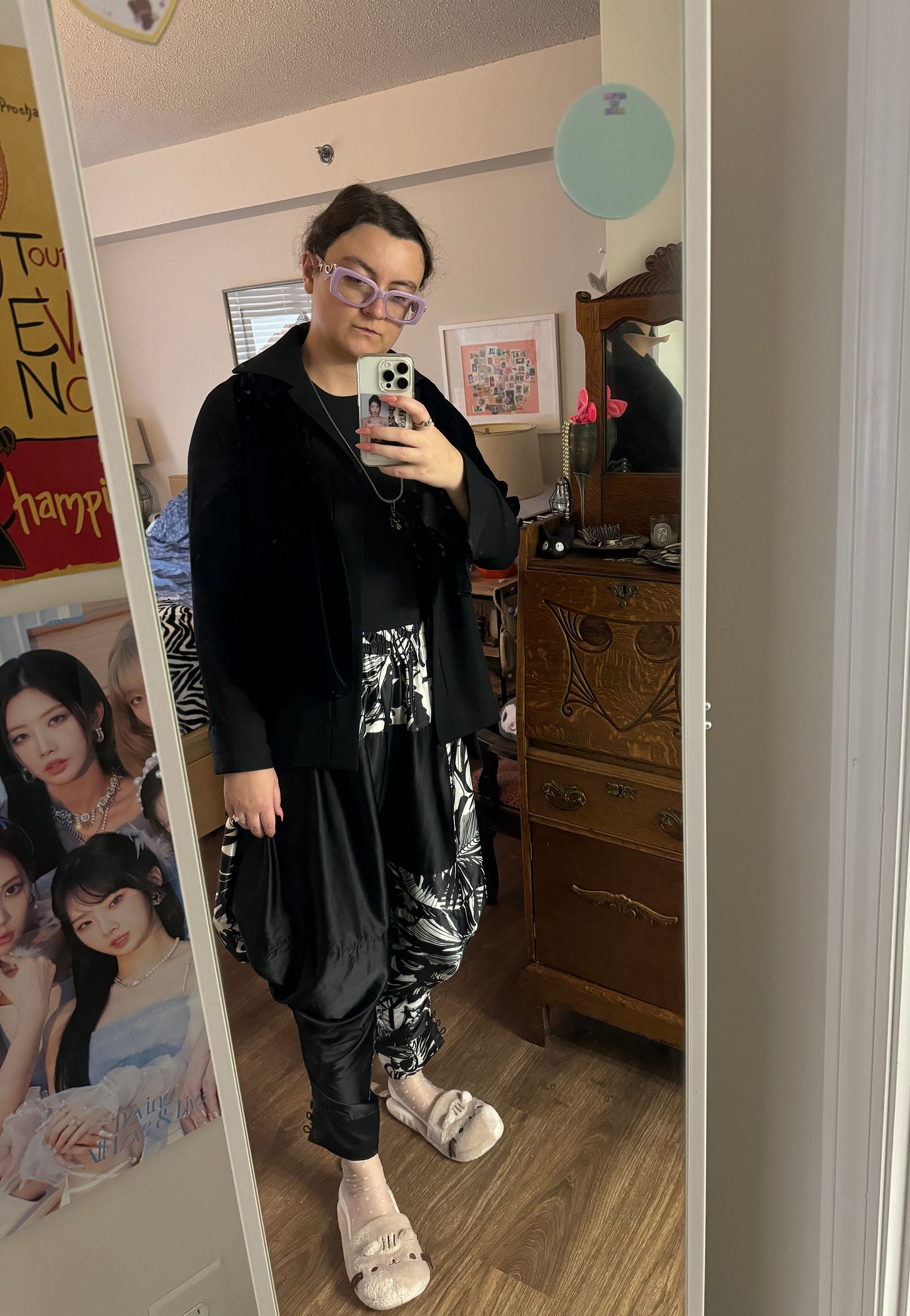 woman wearing a black blazer by yamamoto, a shirt, a multi-print pant with white and black design, white socks, and pusheen slipeprs; taking a selfie in a mirror.