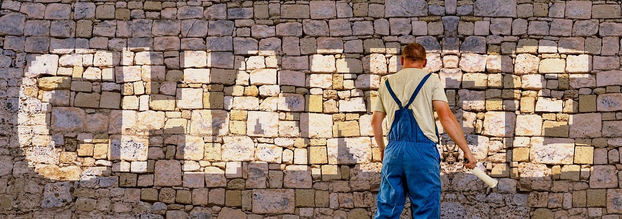 tradesman painting the word "change" on a stone wall