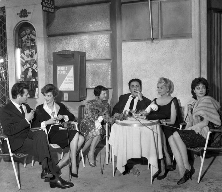 This may contain: a group of people sitting around a table with drinks in front of them on chairs