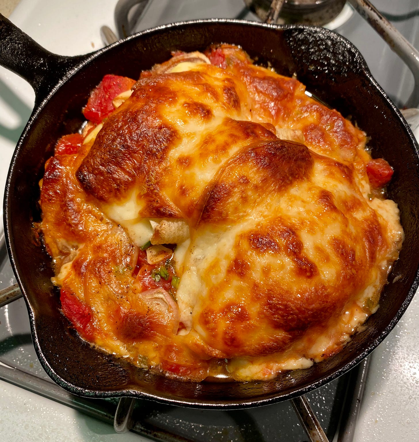 Baked stuffed shells with tomatoes, garlic, shallots, topped with smoked mozzarella in a small pan