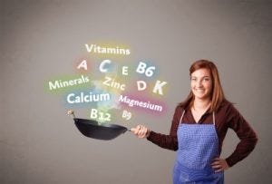 a cook holding a pan with vitamin labels steaming out of the pan.