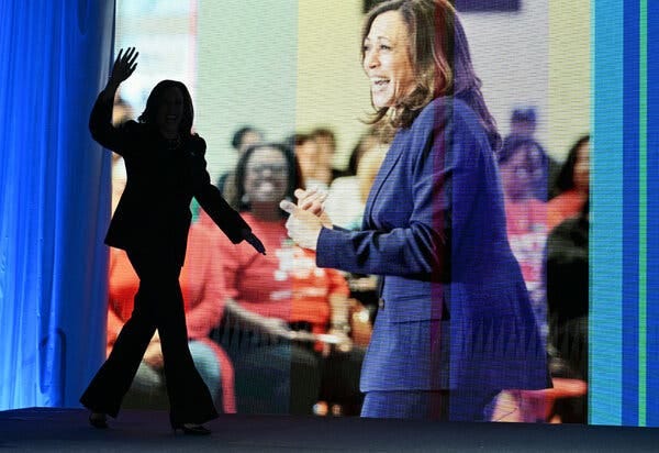 Kamala Harris’s silhouette as she walks onstage with her image as a backdrop.
