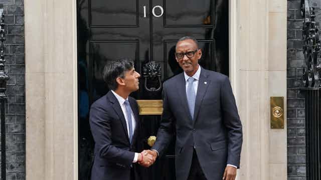 Two men shake hands in front of a door with the number 10 on it Two men shake hands in front of a door with the number 10 on it