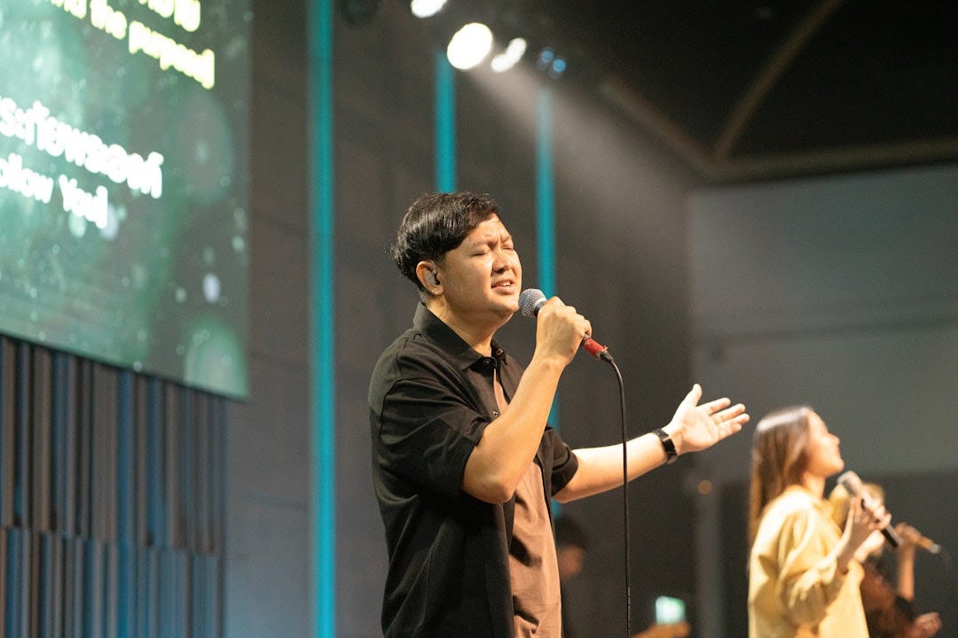 Man singing passionately into a microphone on stage.