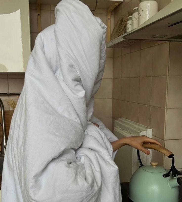 This may contain: a person wrapped in a blanket is cooking on the stove top with a tea kettle