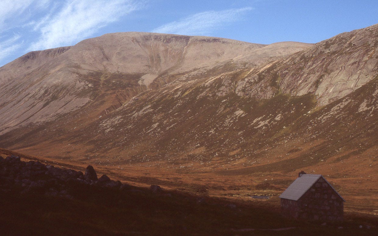 small hut, big stony mountain above