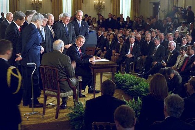 President George W. Bush looks toward Senator Jesse Helms after signing the H.J. Resolution 114 authorizing the use of force against Iraq