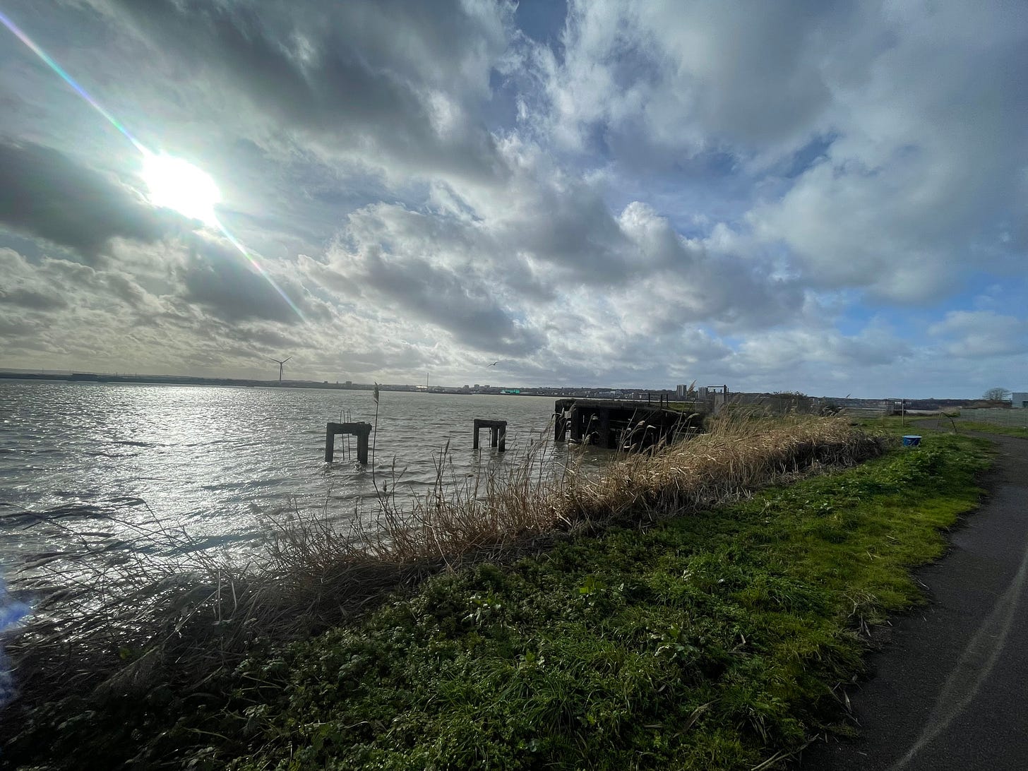 Sun is beaming through clouds over a scuddy Thames River