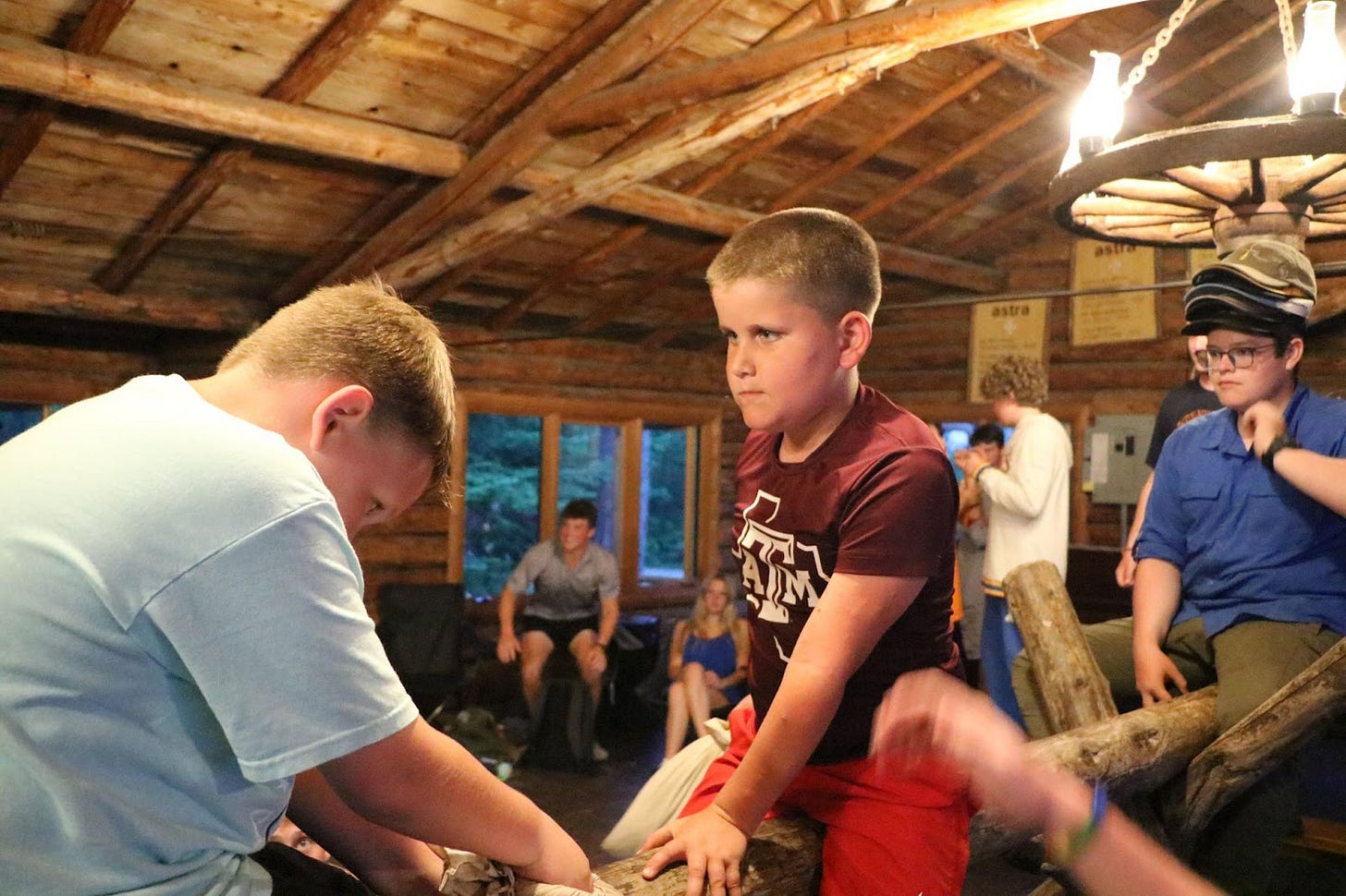 A ten-year-old boy sits confidently atop a log at Camp Kooch-i-ching, ready for a classic camp pillow fight—embodying the quiet strength and self-assurance that comes from hard work and preparation. This moment, captured during a transformative summer in the wilderness, illustrates the true meaning of confidence as explored in our personal growth story on Substack